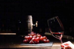 Copa de vino tinto con uvas y barrica